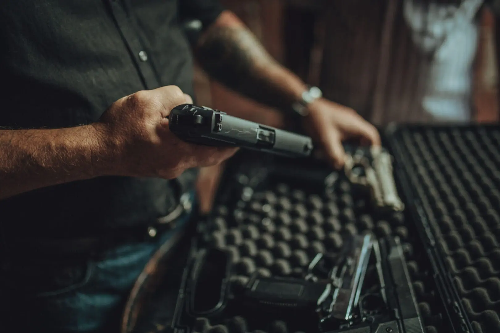 Person handling gun near protective case.