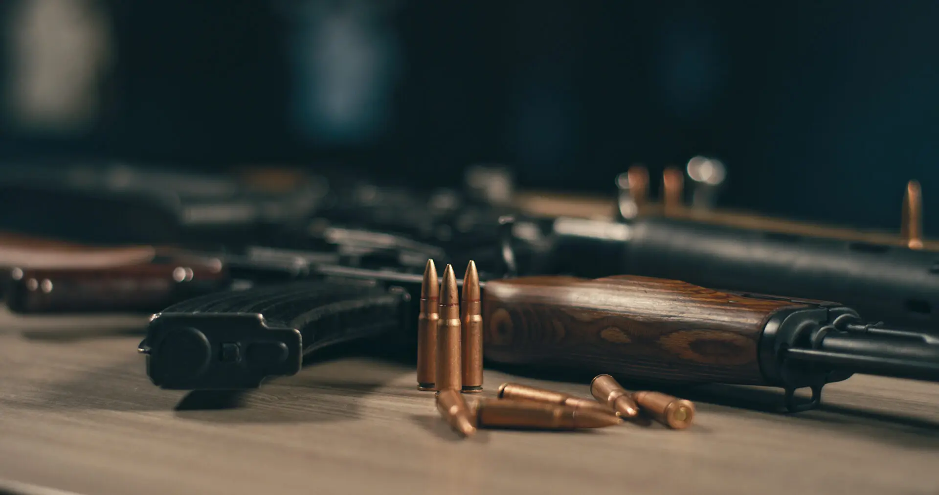 Rifles and bullets on a wooden table.