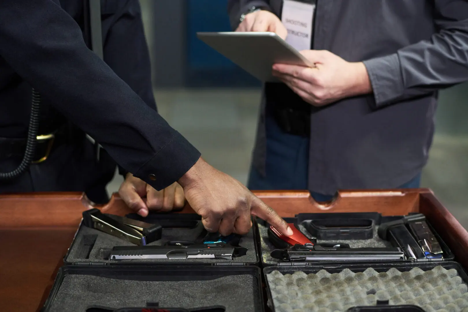 Two people inspecting handguns in case.